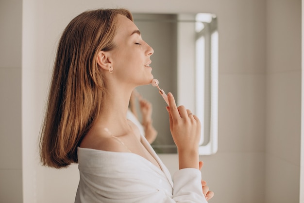 Woman doing self massage with rose quartz face roller