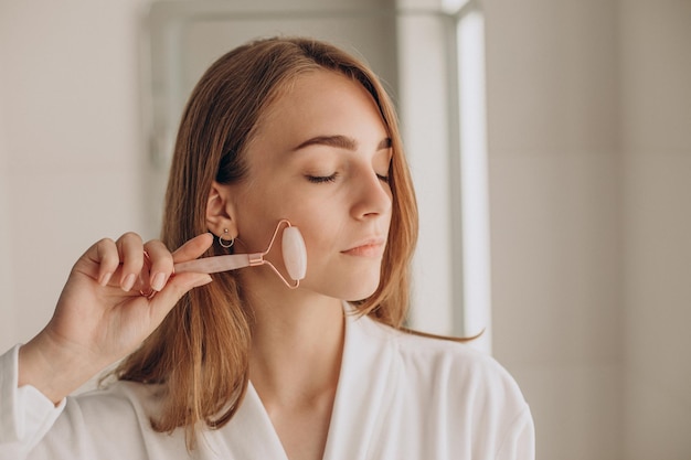 Woman doing self massage with rose quartz face roller