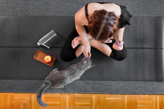 Woman doing sport indoors next to her cat