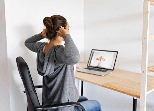 Photo woman doing stretching yoga at her office by online sport video.