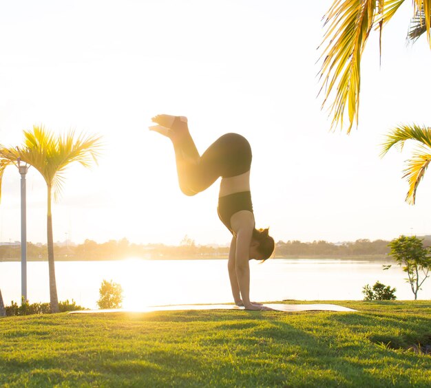 Foto donna che fa yoga contro il cielo durante il tramonto