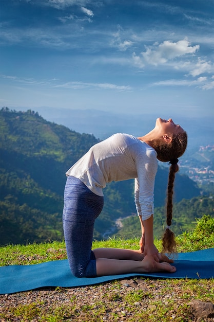 Woman doing yoga asana Ustrasana camel pose outdoors