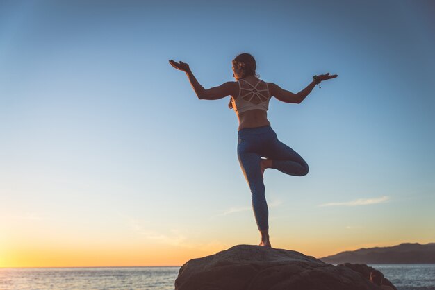 Donna che fa yoga sulla spiaggia