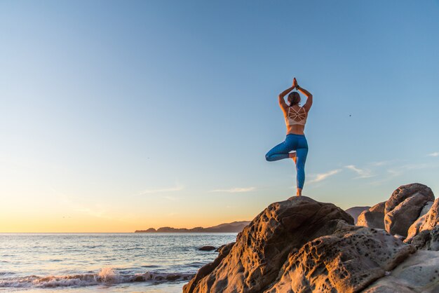 Woman doing yoga on the beach