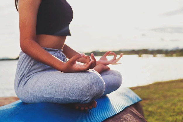 Photo woman doing yoga by the lake in the evening