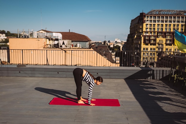 Woman doing yoga exercises on house roof in early morning