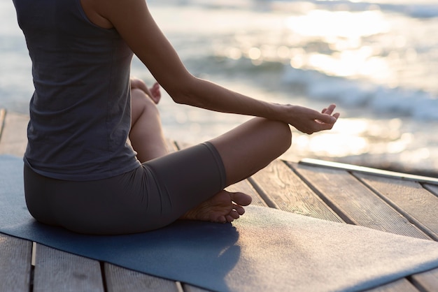 Foto donna che fa yoga di fronte al mare