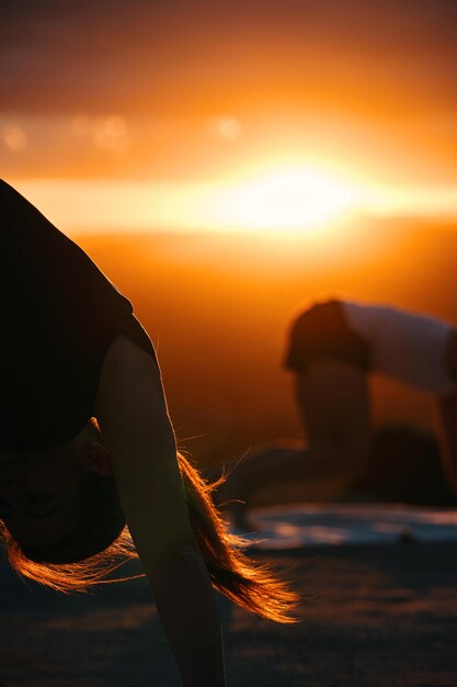 Женщина занимается йогой перед закатом