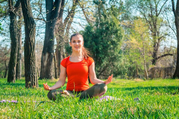 Woman doing yoga on the green grass