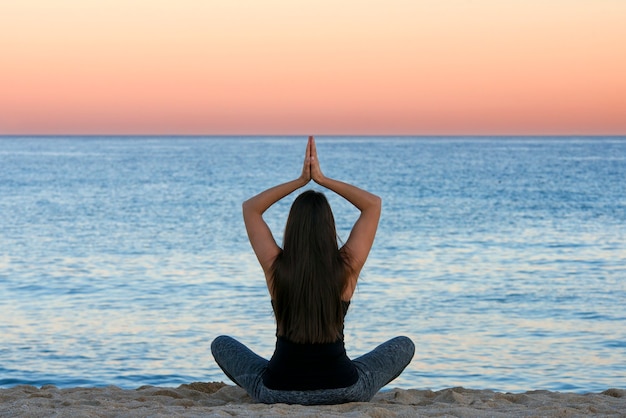 Woman doing yoga and meditation in front of the sea