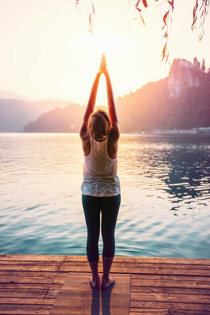 Foto donna che fa yoga sul molo contro il lago