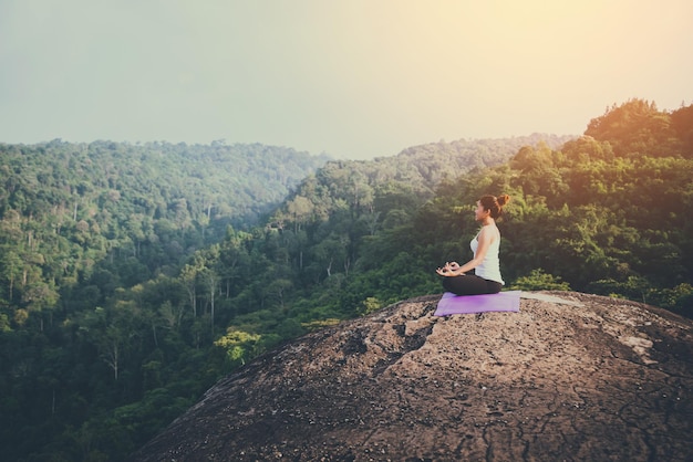 Woman doing yoga on rock