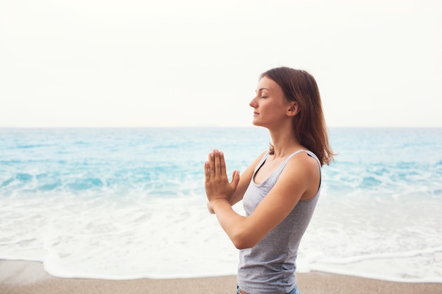 Woman doing yoga on the sea background