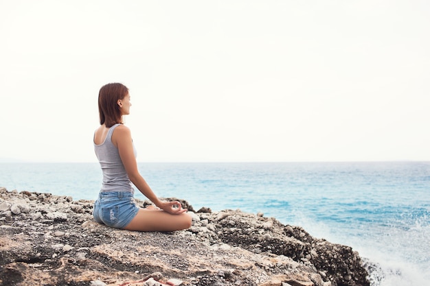 Woman doing yoga on the sea background