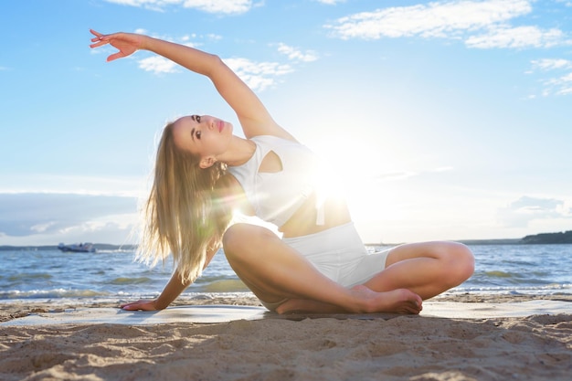 Woman doing yoga on the shore  crossed legs  side stretch  su