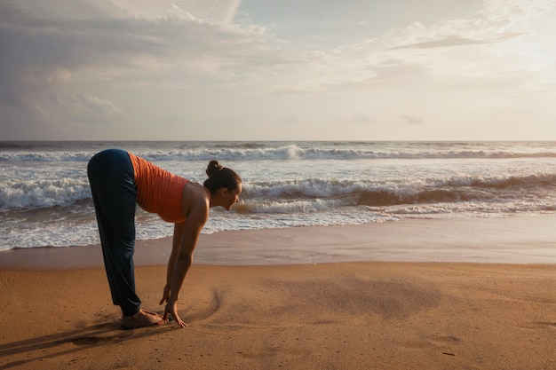 해변에서 여자 요가 일 인사말 Surya Namaskar