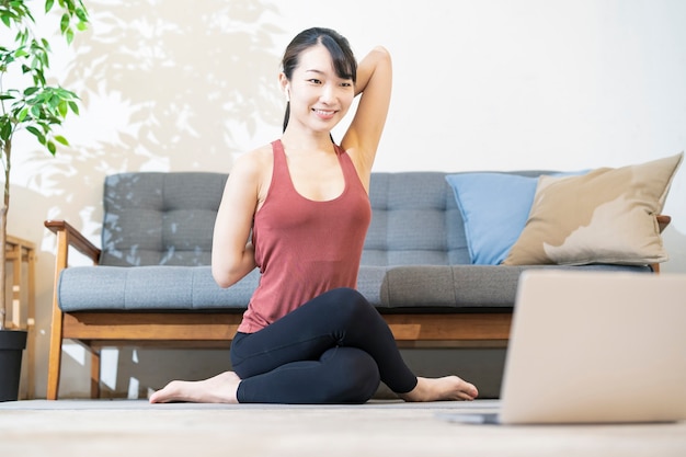 Una donna che fa yoga mentre guarda lo schermo del computer nella stanza