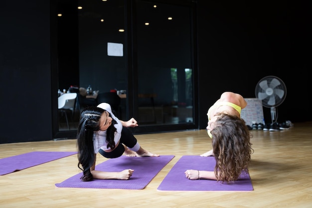 Woman doing yoga with trainer gradually teaching