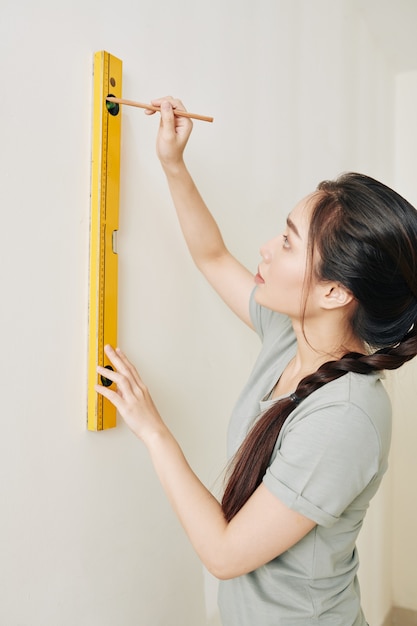 Woman drawing line on wall