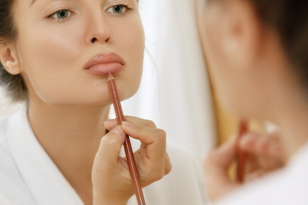 Woman drawing lip contour