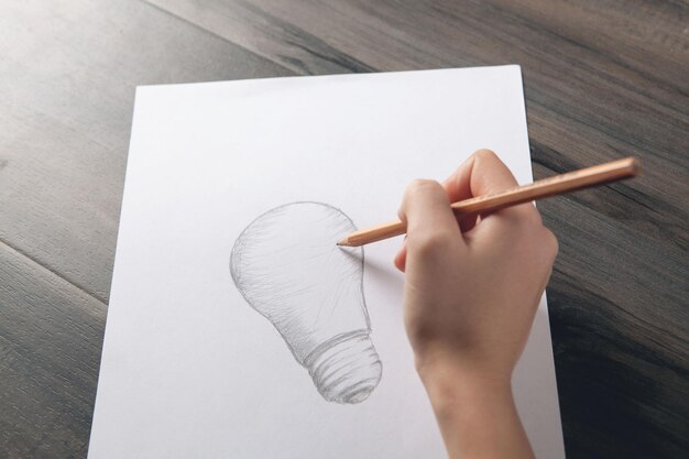 Woman draws a light bulb on paper