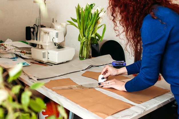 a woman draws a pattern of a dress on the fabric with soap in front of her mobile phone