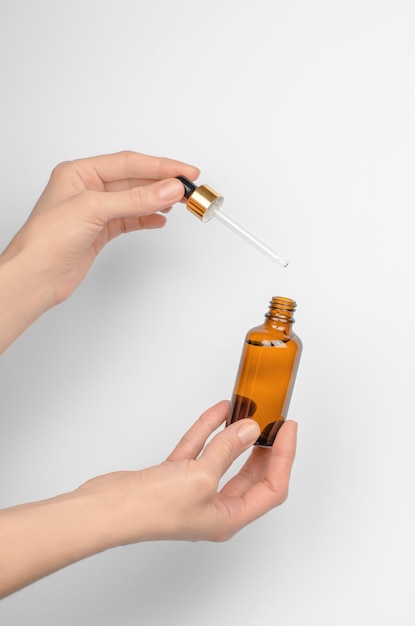 Woman draws serum or essential oil from a cosmetic bottle with a pipette Female hands hold a bottle with a pipette Beauty and skin care concept