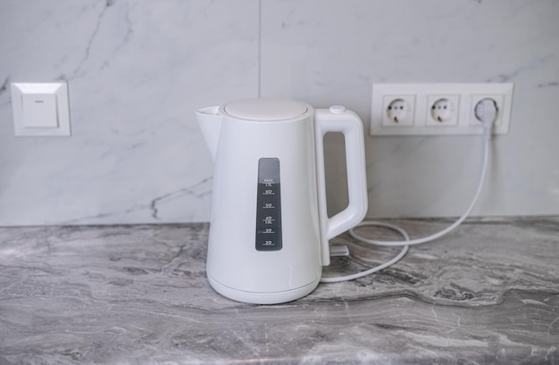 A woman draws water into an electric kettle in the background of the kitchen It's time for breakfast and tea Modern electric kettle Kettle for boiling water