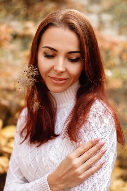 Woman in dress and hat on background of autumn foliage