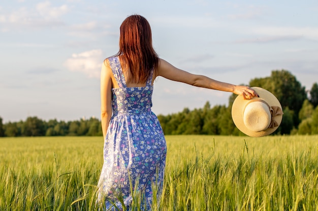 Woman in a dress and hat walking on a field