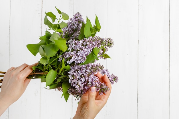 Woman in dress holding a big branch of lilac flower in her hand