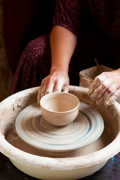 Photo woman in dress modeling in clay on a potter's wheel