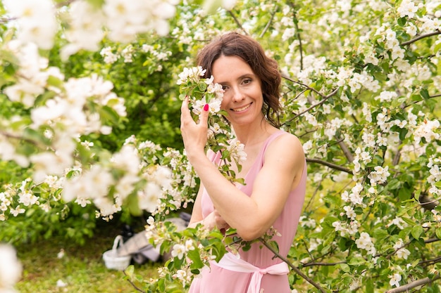 Una donna in un vestito vicino a un albero di primavera in fiore romantico stato d'animo felice