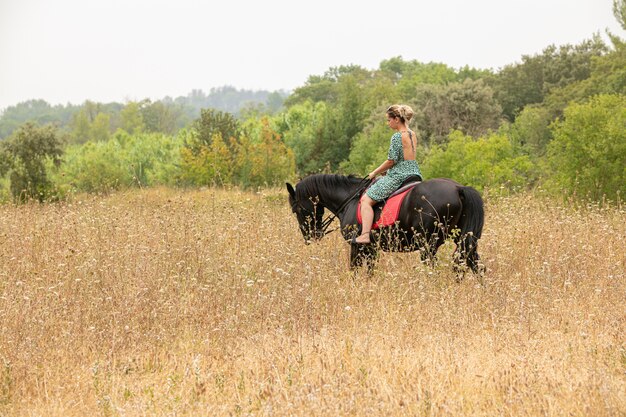 Donna in un vestito a cavallo nella natura