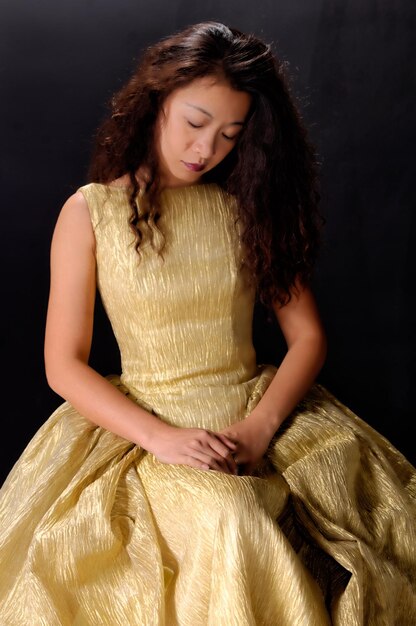 Photo woman in dress sitting against black background