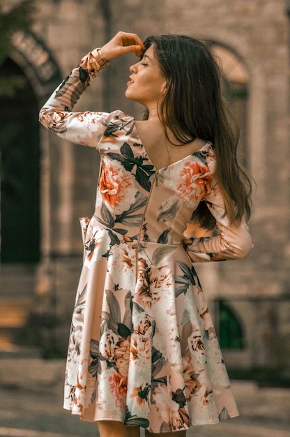 服を着た女性が建物の向こうに立っています