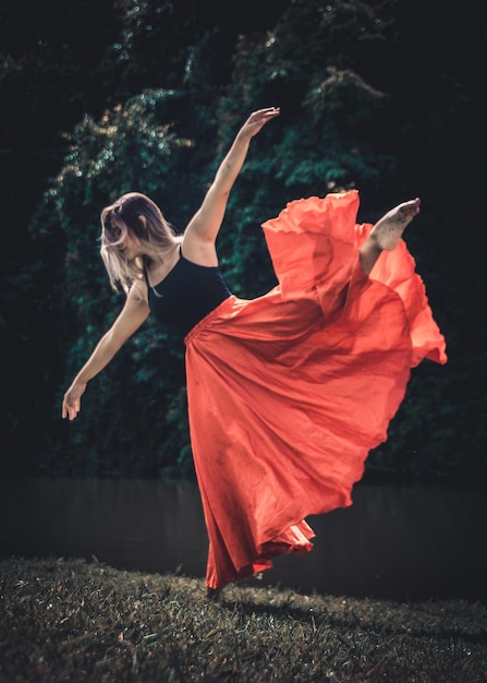 woman in dress standing on one leg outdoors