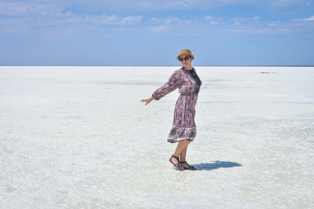 Woman in dress on a white salt lake portrait of a woman on a white salt lake woman in hat and glasses on a white salt lake