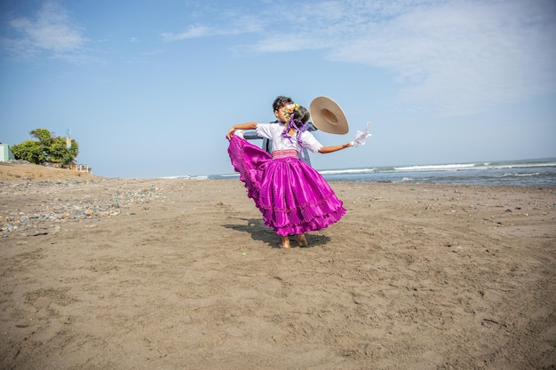 a woman in a dress with a hat on her head is dancing on the beach