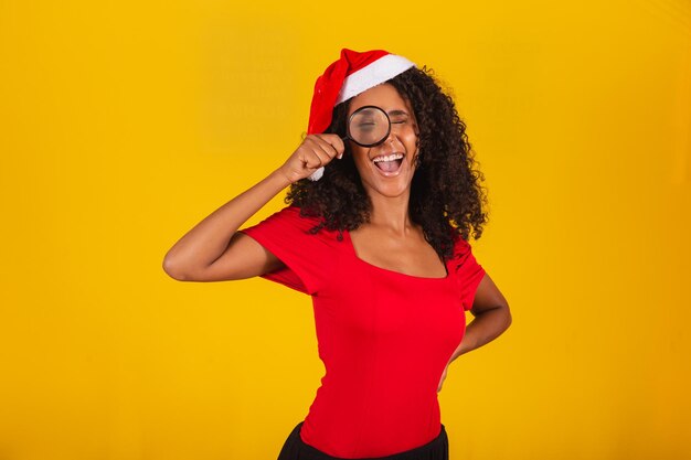 Woman dressed for christmas in santa hat wearing a magnifying glass