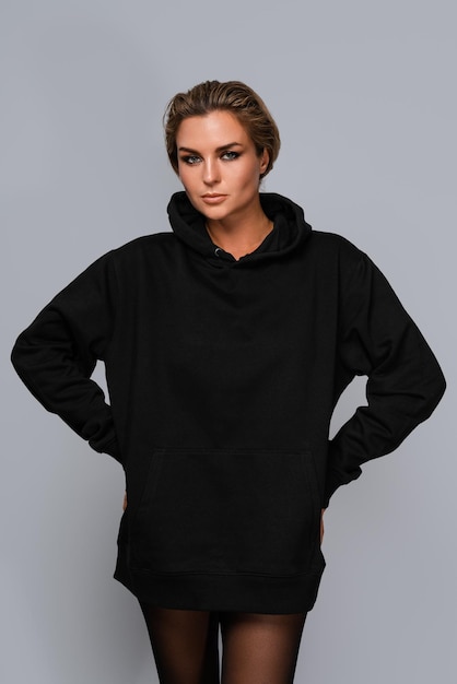 Фото Женщина, одетая в черный огромный капюшон с пустым пространством, идеально подходит для макета, установленного на сером