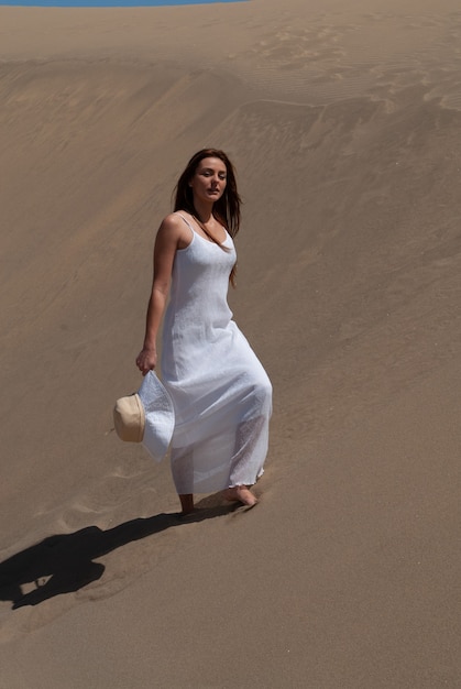 woman dressed in white enjoying the sand dunes on a sunny spring or summer day