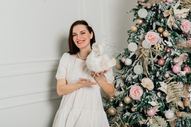 Woman dressing Christmas tree, smiling, sitting in new year interior