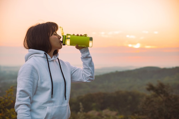 日の出の運動の後、女性はボトルから水を飲む