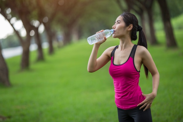 女性は運動の水を飲む。