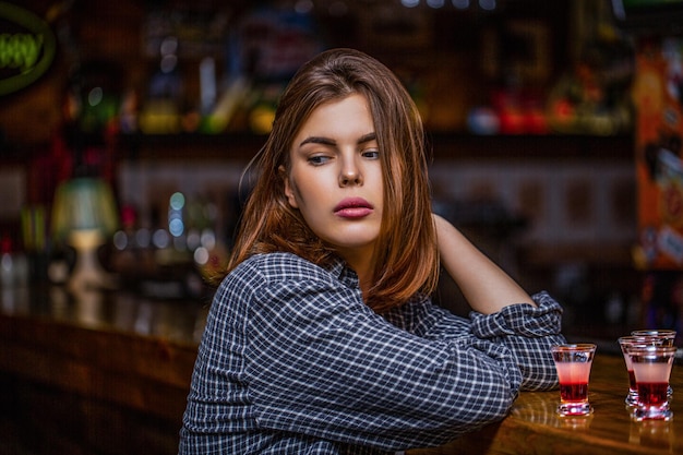 Photo woman drinking alcohol scotch whiskey glass isolated at bar or pub in alcohol abuse and alcoholic concept drunk woman holding a glass of whisky or rum woman in depression