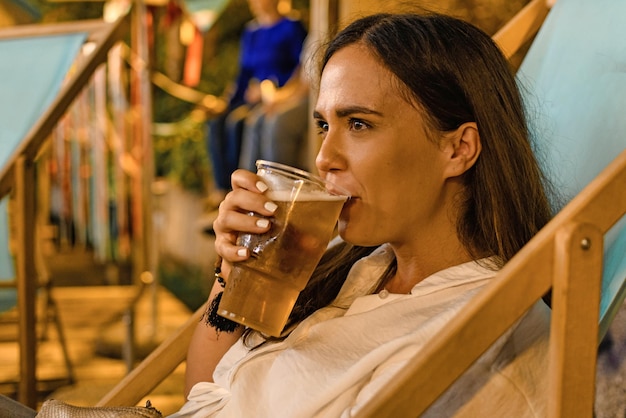 Photo woman drinking beer while sitting in restaurant