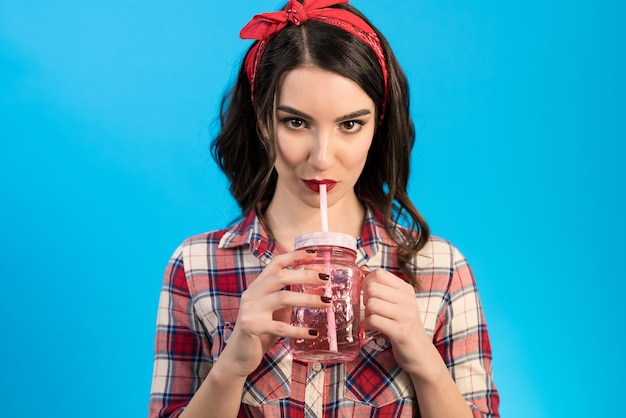 The woman drinking a beverage on the blue background