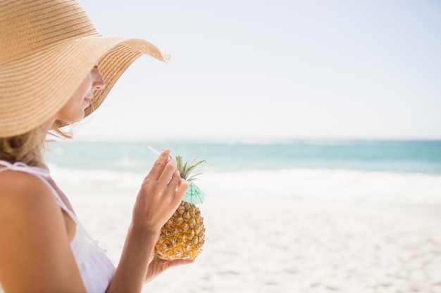 Woman drinking cocktail in pineapple