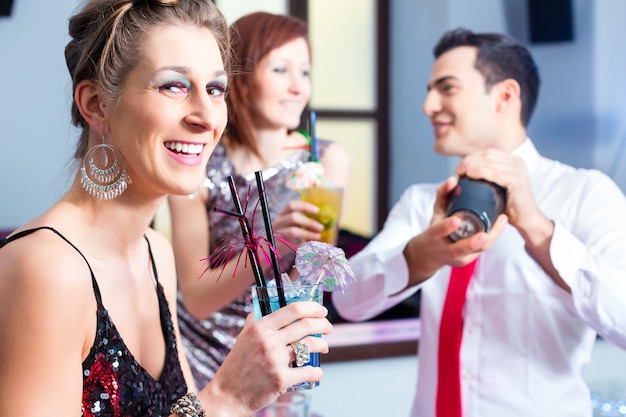 Женщина пьет коктейли в модном ночном клубе